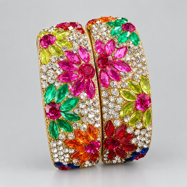 Decorative bangles with floral designs and gemstones on a white glove.